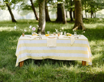 Table set with a yellow and white striped tablecloth in a park setting